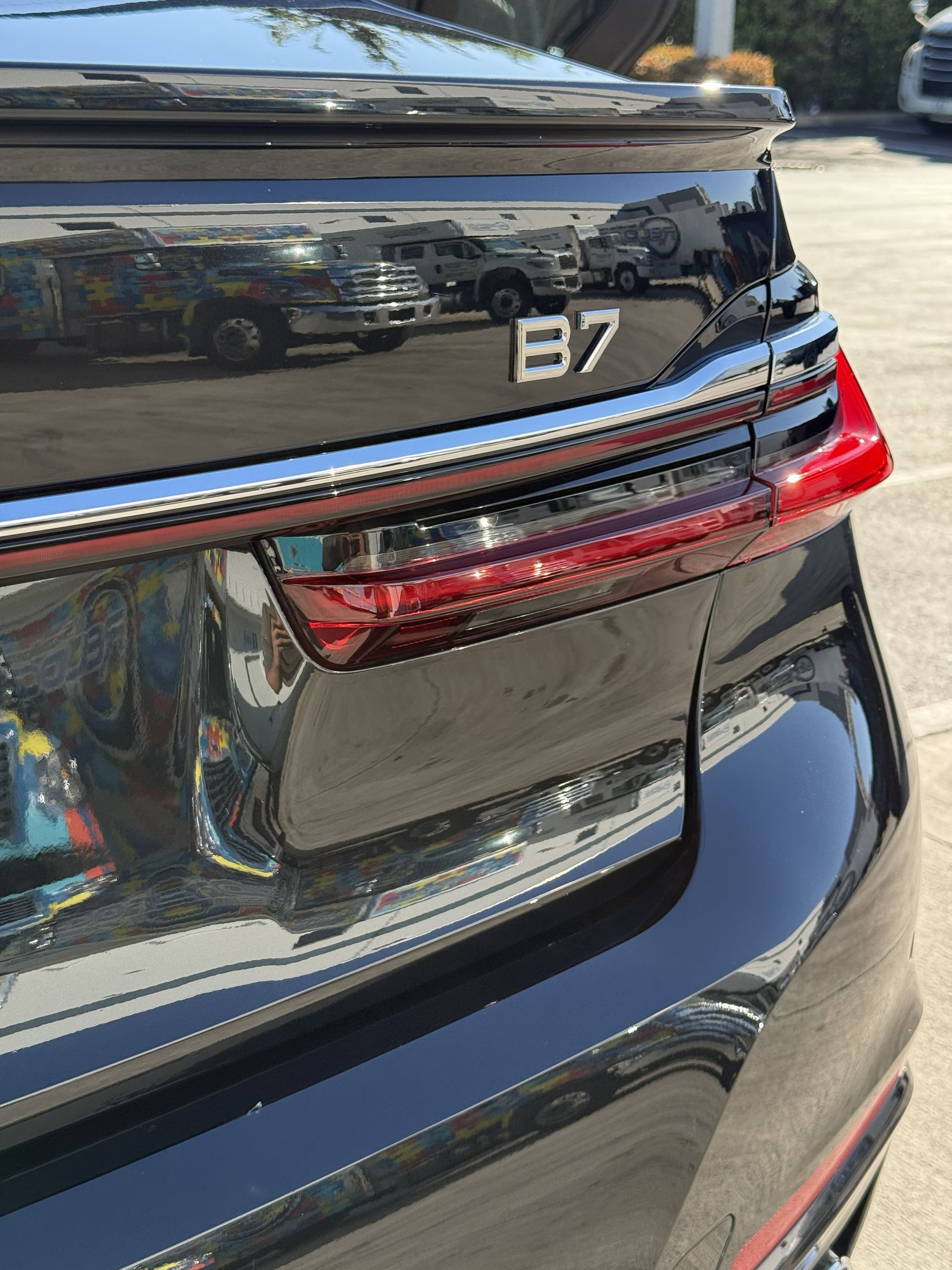 Close-up view of the rear taillight and a B7 emblem on a black luxury sedan.