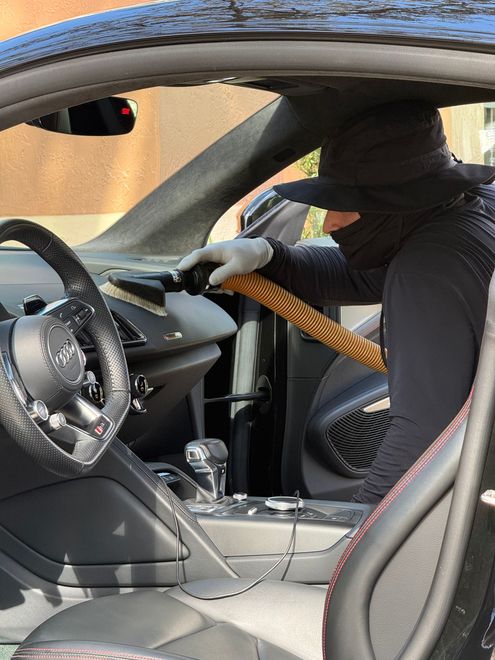 Masked person reaching through a car window with a crowbar toward the dashboard.