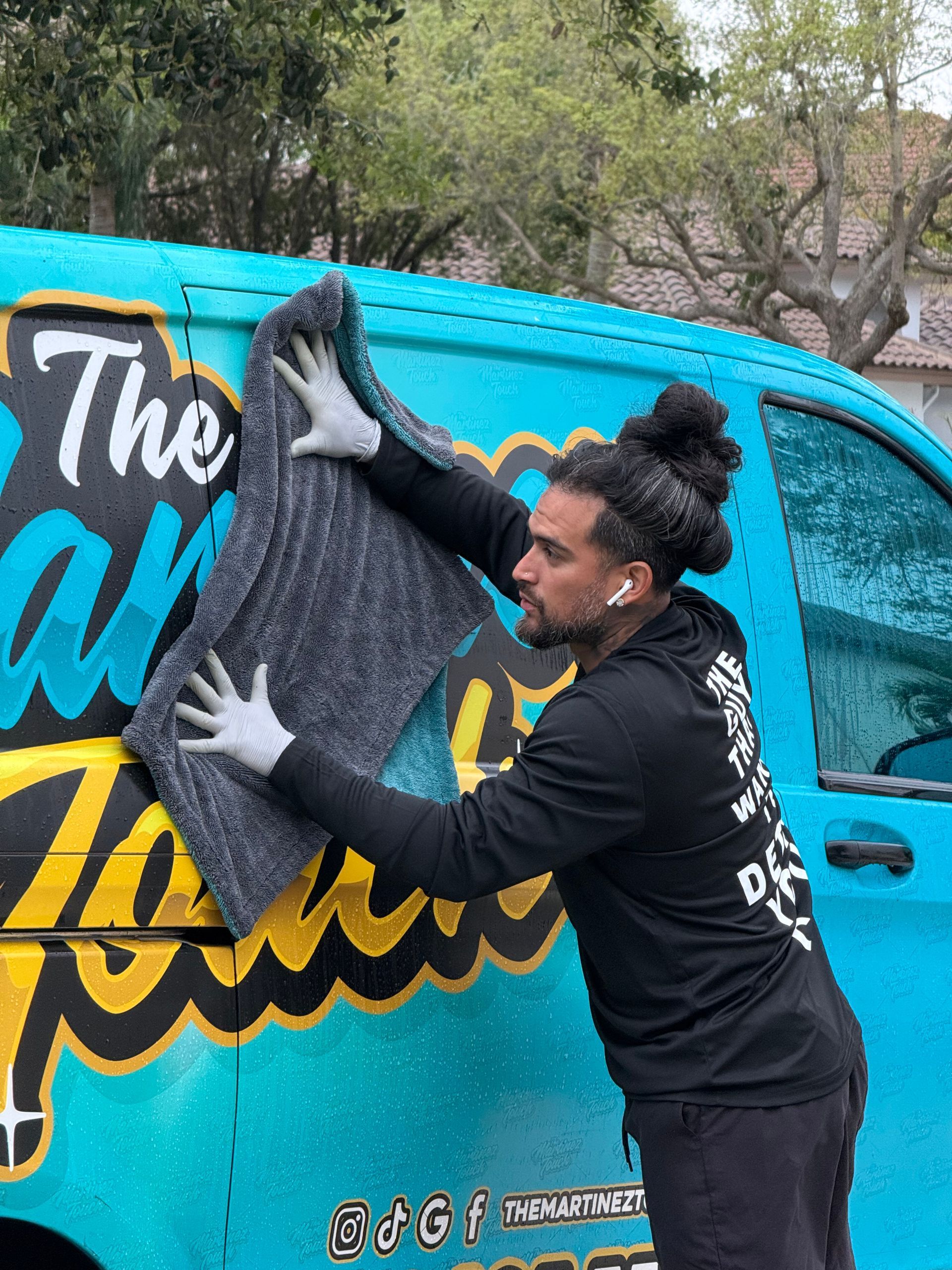 Person applying a gray mural decal to a turquoise van with colorful lettering.