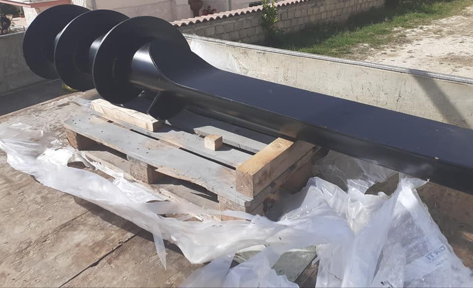 Trivella nera su un pallet di legno all'aperto, probabilmente per la perforazione.