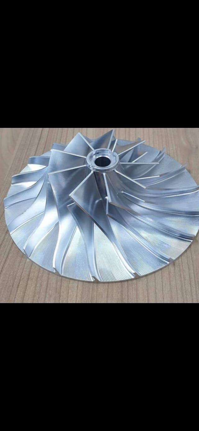 Girante del turbocompressore in argento su una superficie di legno.