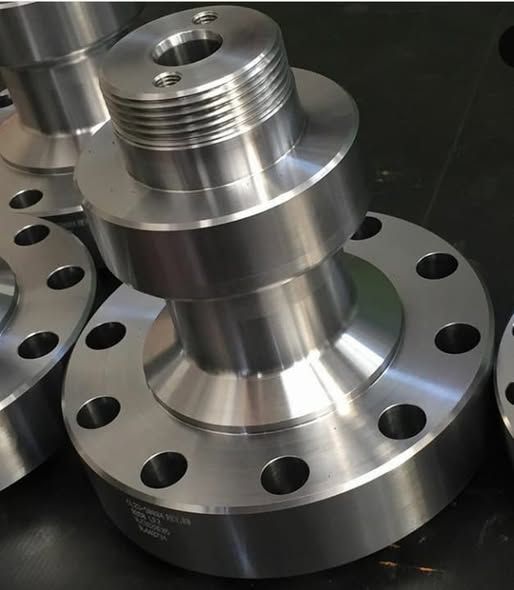 Primo piano di parti metalliche lavorate, probabilmente flange, con sezioni filettate e flangiate.