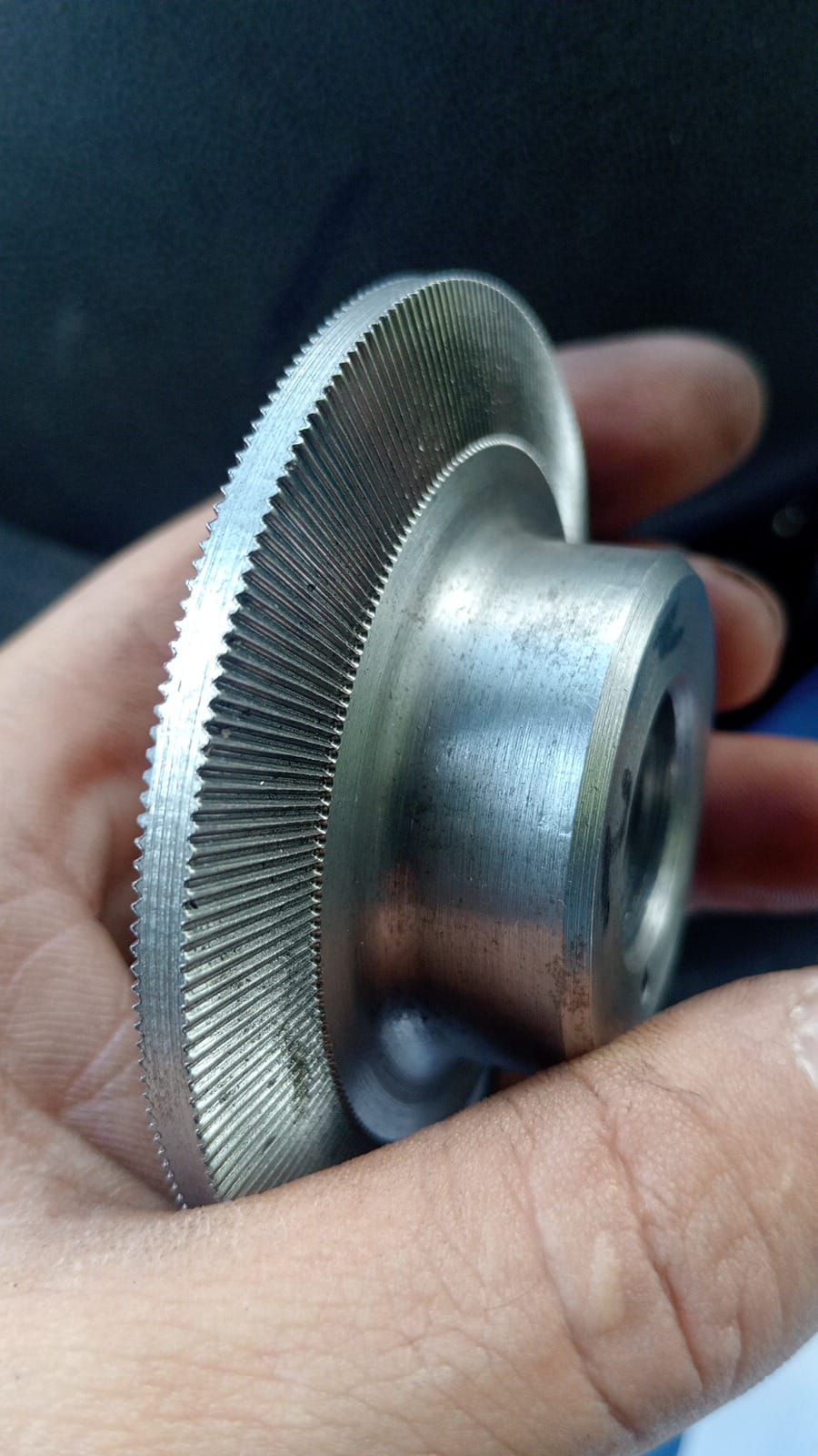 Un pezzo di metallo con un bordo esterno dentato, tenuto in mano.