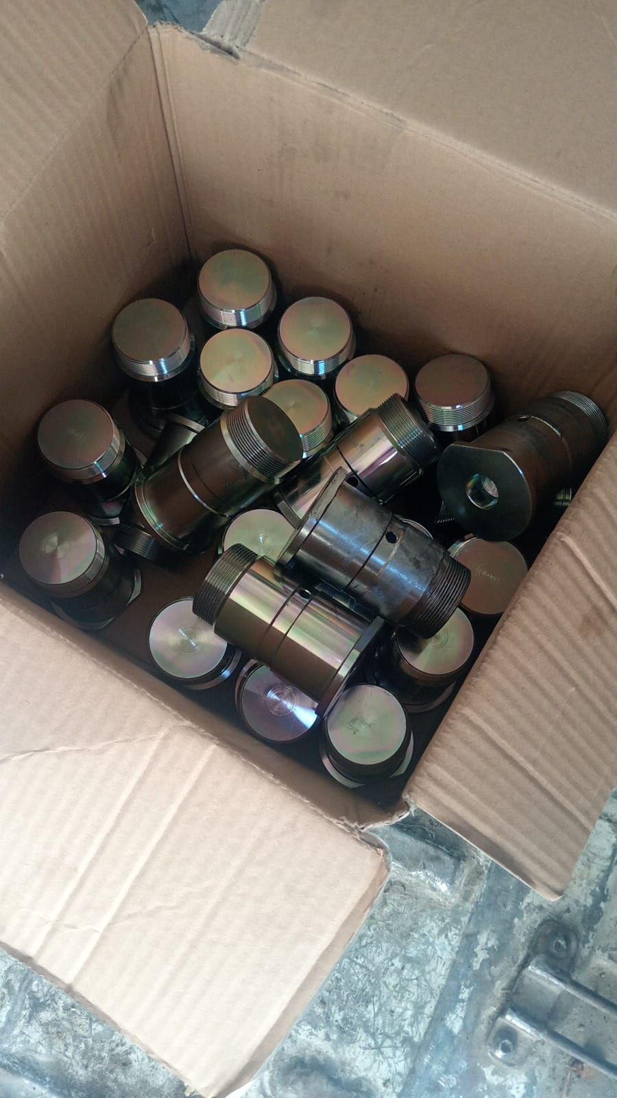 Scatola piena di parti cilindriche di motori metallici, con parte superiore piatta e lati cilindrici.