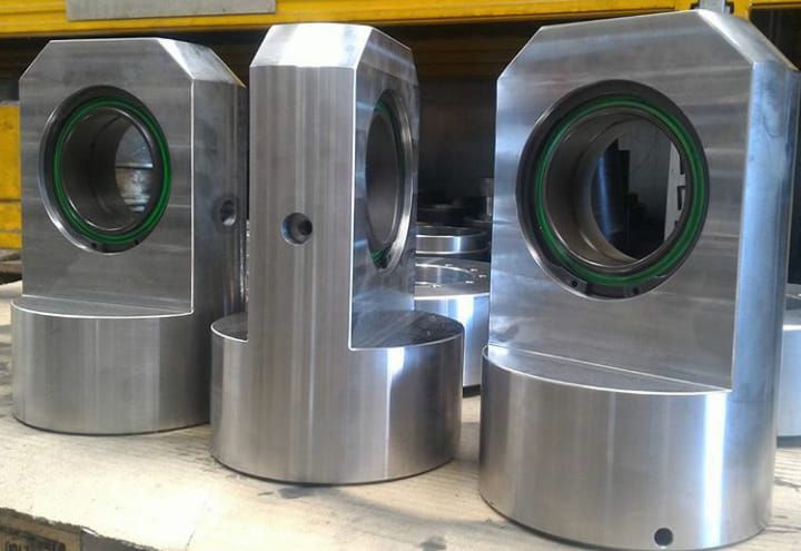 Tre parti metalliche della macchina con guarnizioni verdi; una ha un piccolo foro.