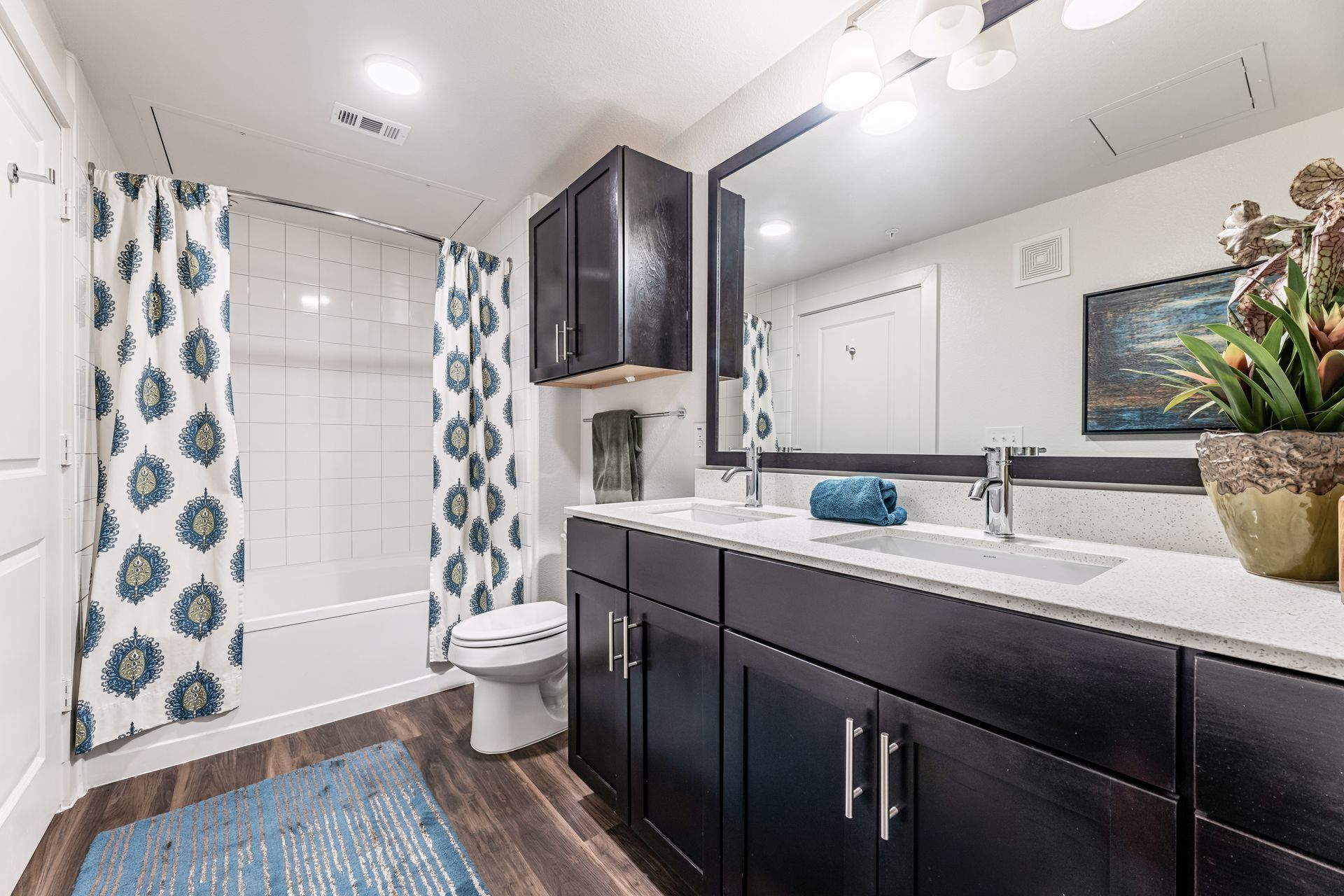 Apartment bathroom with two sinks, a toilet, and a shower curtain.