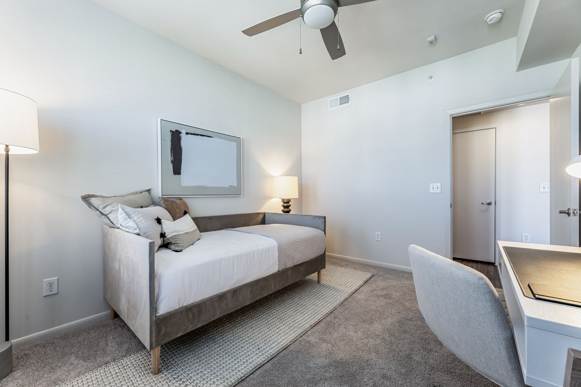 A bedroom with a bed, desk, chair, and ceiling fan at Parkside at Craig Ranch.