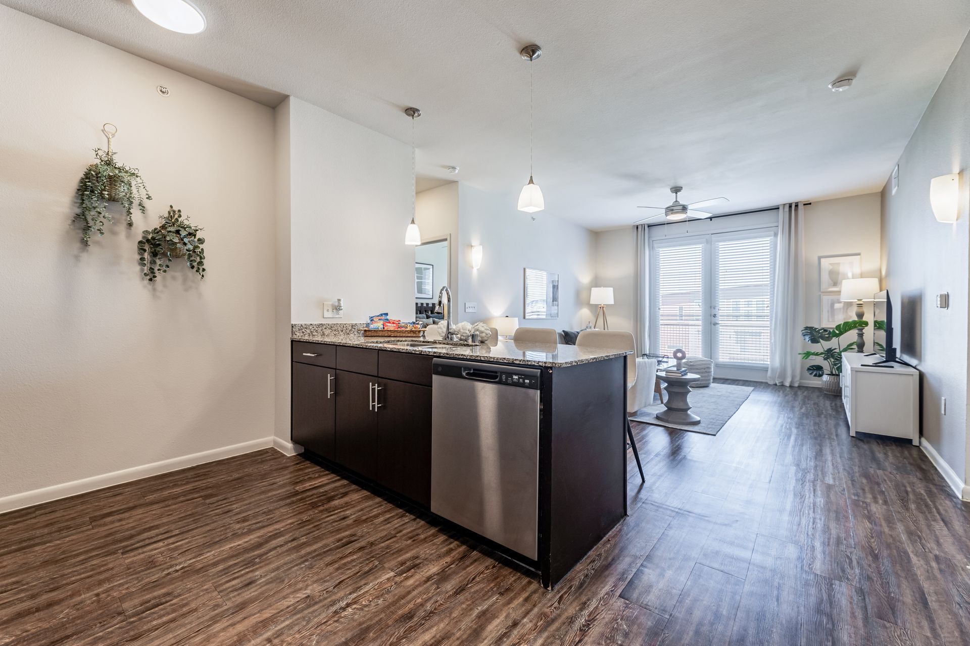 Apartment kitchen with stainless steel appliances and wooden floors in a living room at Parkside at Craig Ranch.
