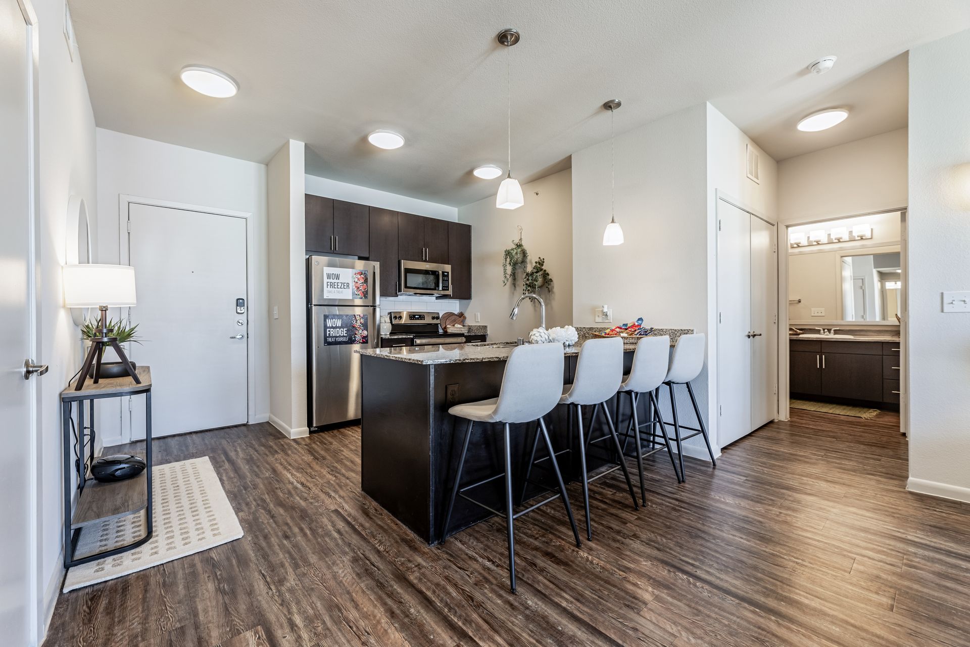 A kitchen with stainless steel appliances, wooden floors, and a large island at Parkside at Craig Ranch.