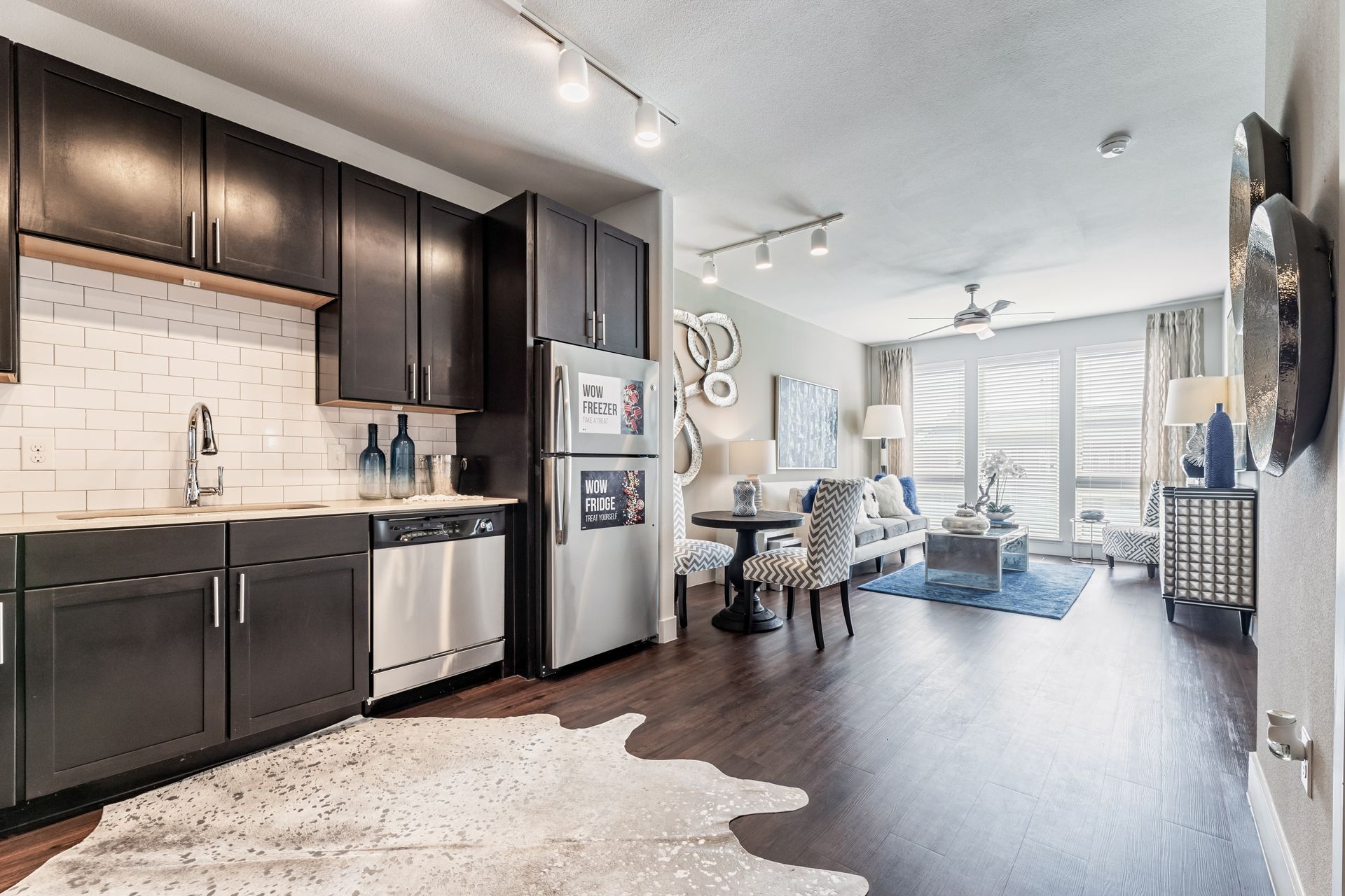 A kitchen with black cabinets and stainless steel appliances and a rug on the floor at Parkside at Craig Ranch.