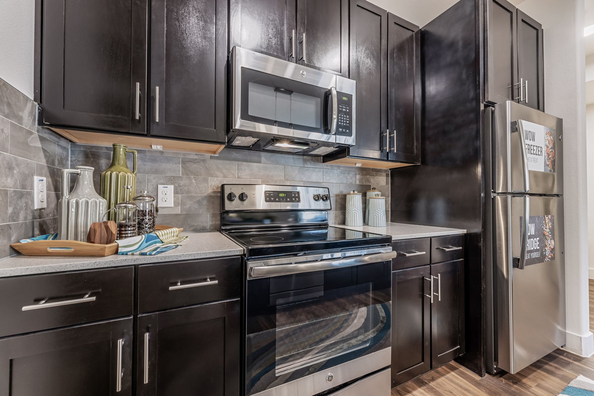 A kitchen with stainless steel appliances and black cabinets at Parkside at Craig Ranch.
