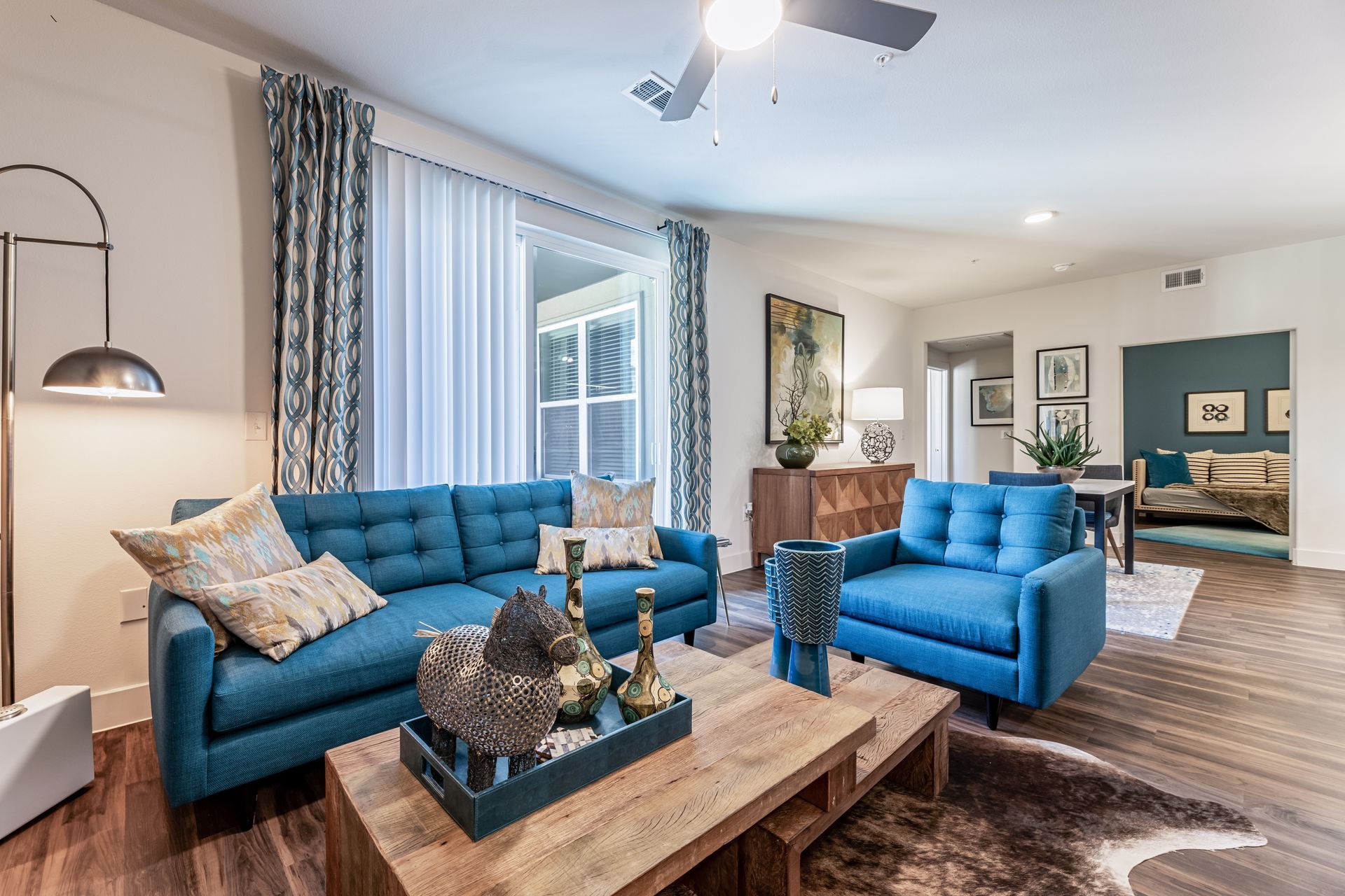 Parkside at Craig Ranch apartment living room with two blue couches, a coffee table, and a ceiling fan.