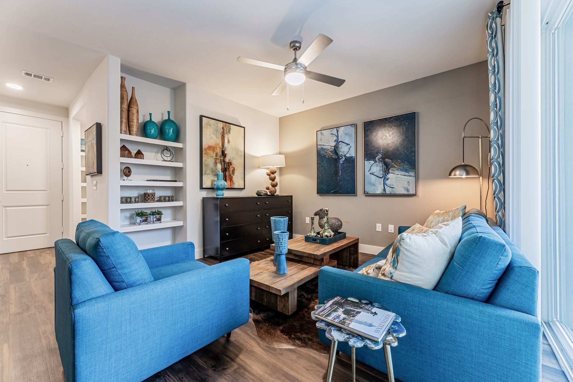 Apartment living room with blue furniture and a ceiling fan at Parkside at Craig Ranch.