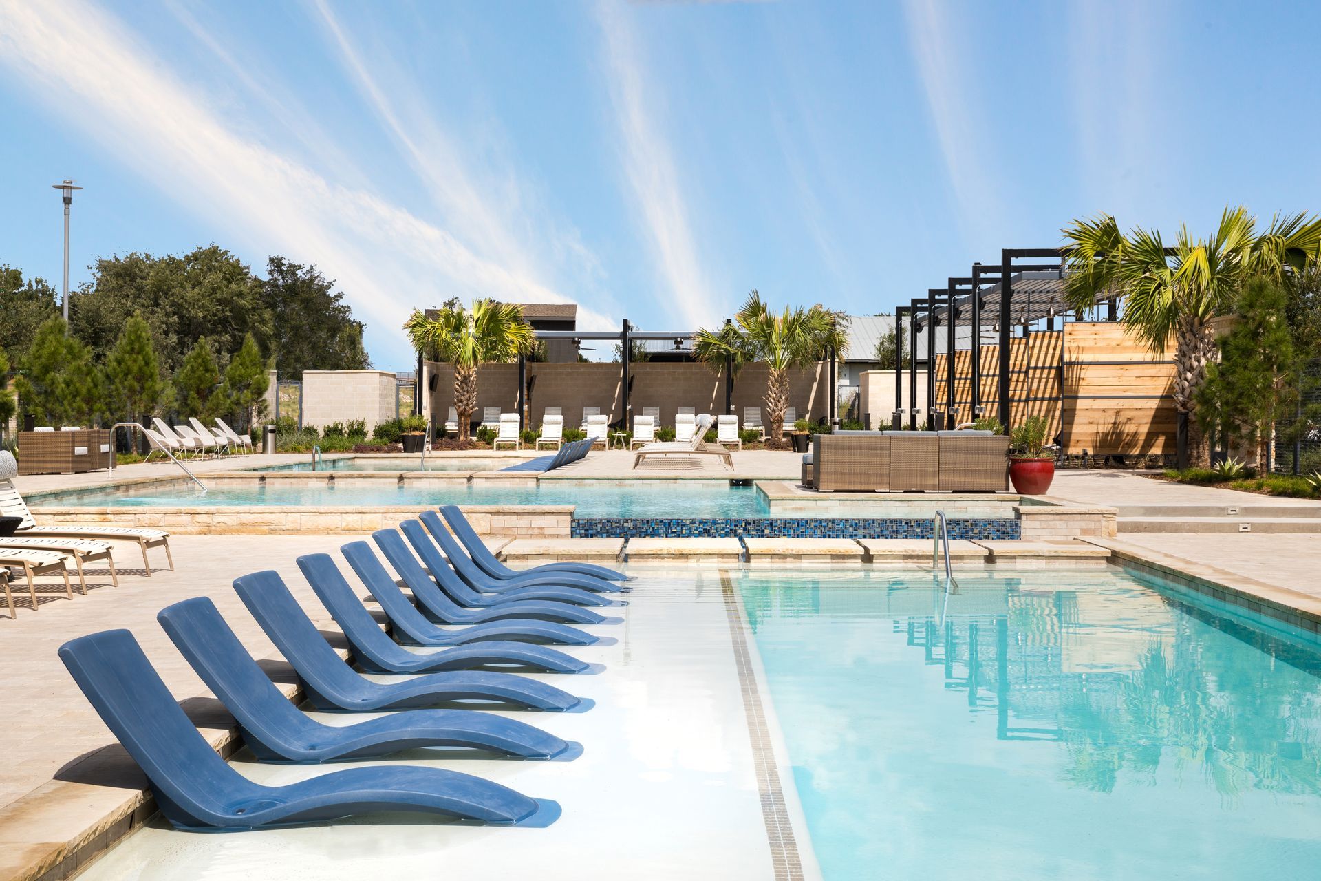 A row of blue lounge chairs are lined up next to a large swimming pool at Parkside at Craig Ranch.