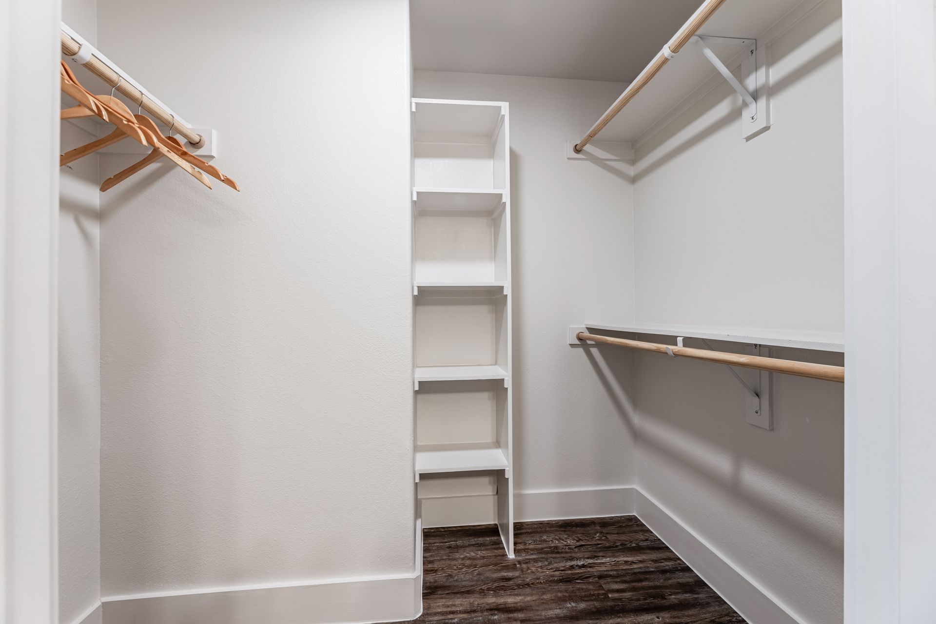 A walk-in closet with a wooden floor and shelves at Parkside at Craig Ranch.