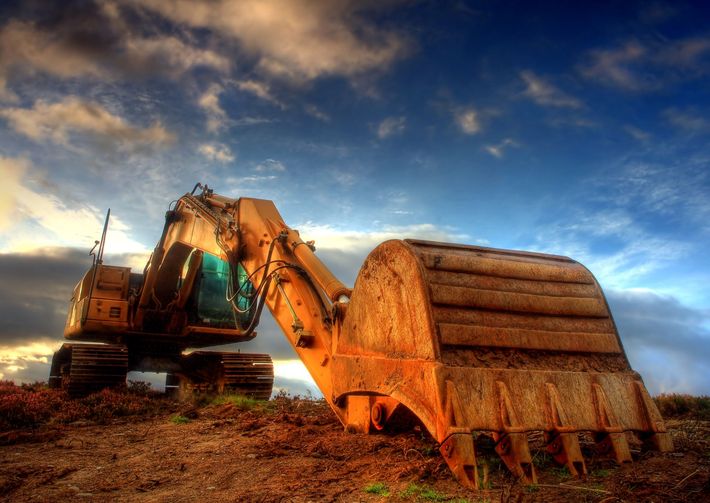 An excavator is sitting in the dirt with a blue sky in the background