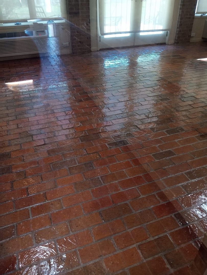 A living room with a brick floor and a window.