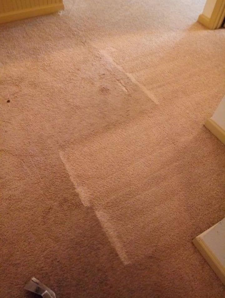 A vacuum cleaner is sitting on a dirty carpet in a room.
