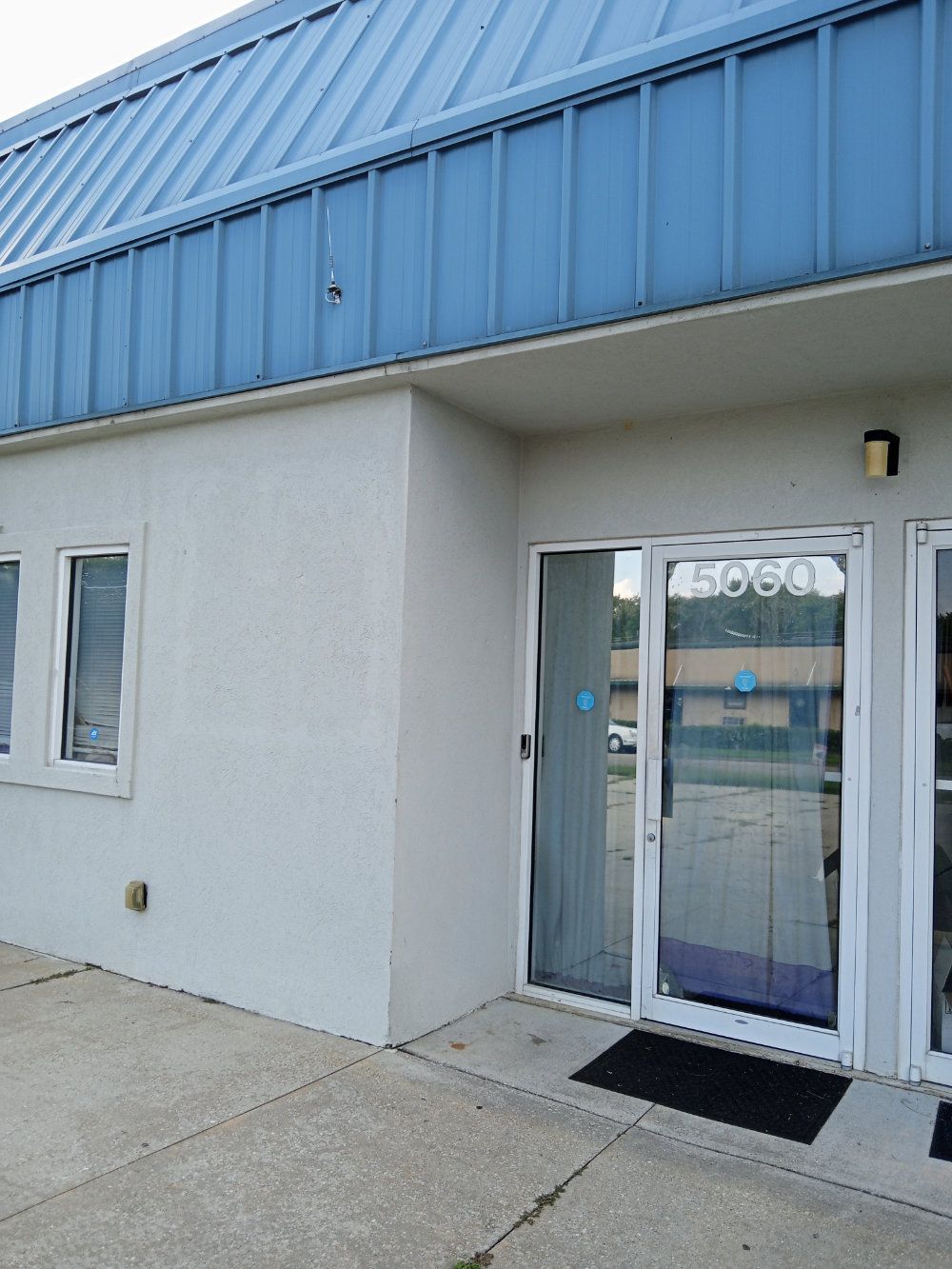 A white building with a blue roof and glass doors