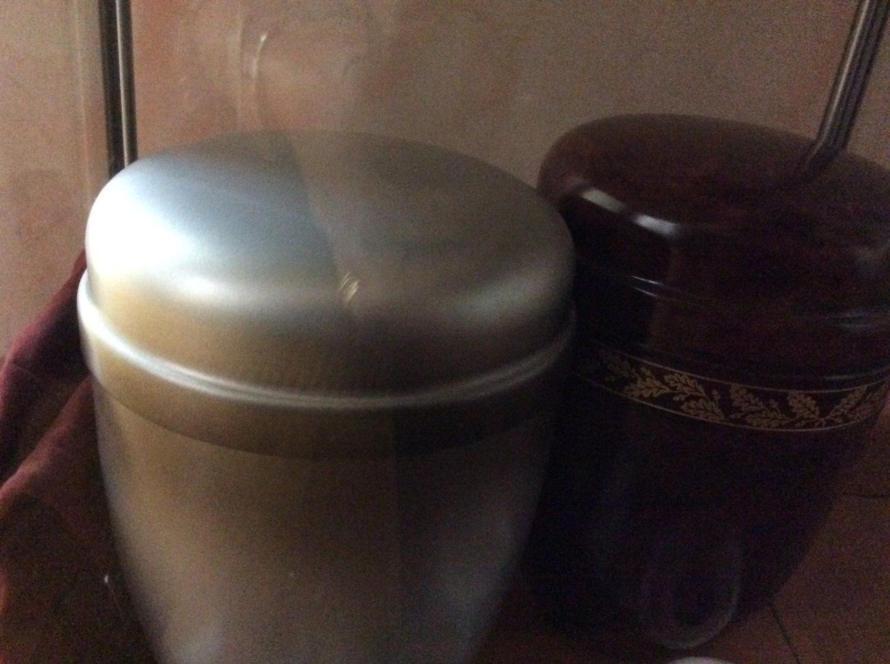 Due urne: una in metallo color argento, l'altra marrone scuro con finiture dorate, una accanto all'altra.