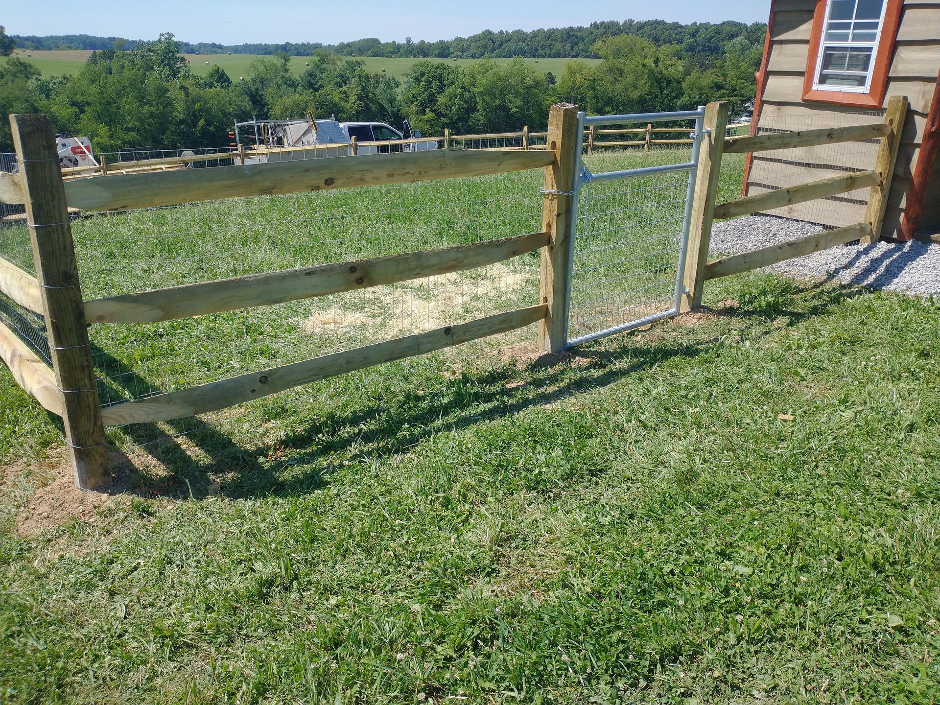 Wooden fence with a gate in a grassy field.