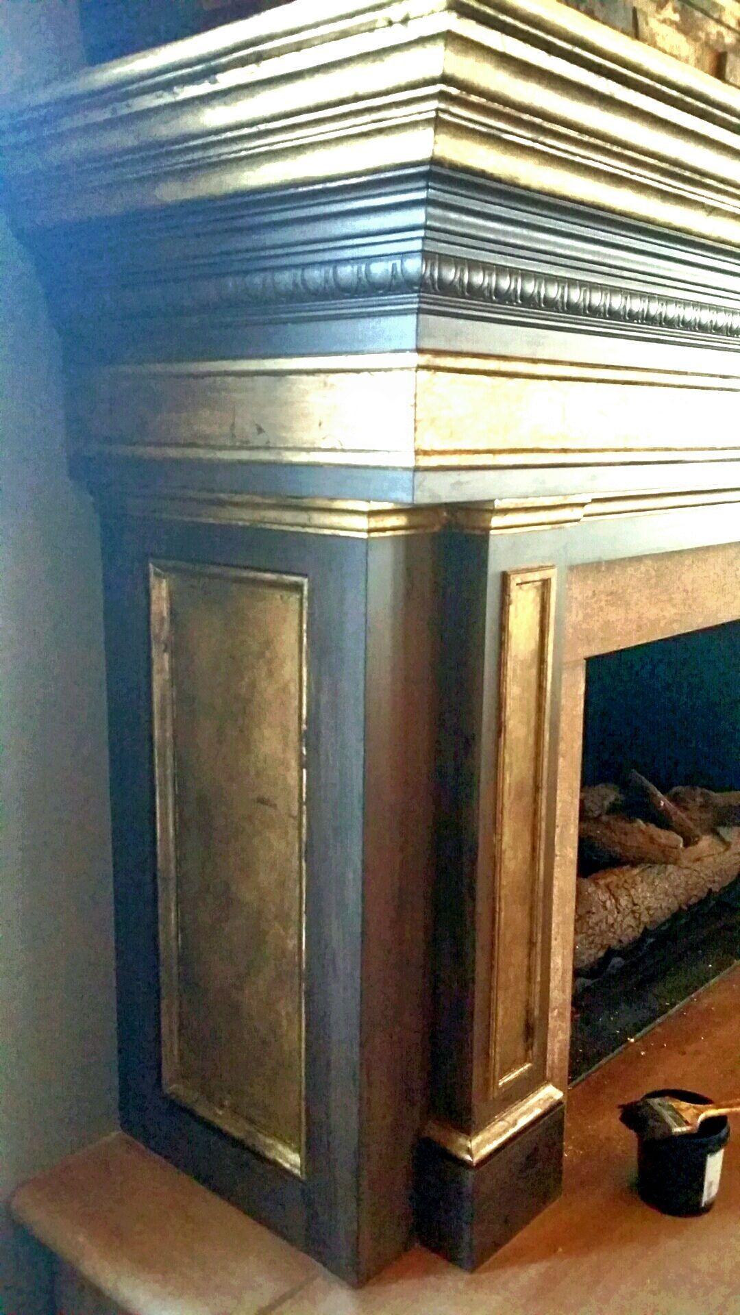 A fireplace with a gold trim and a wooden mantle in a living room.