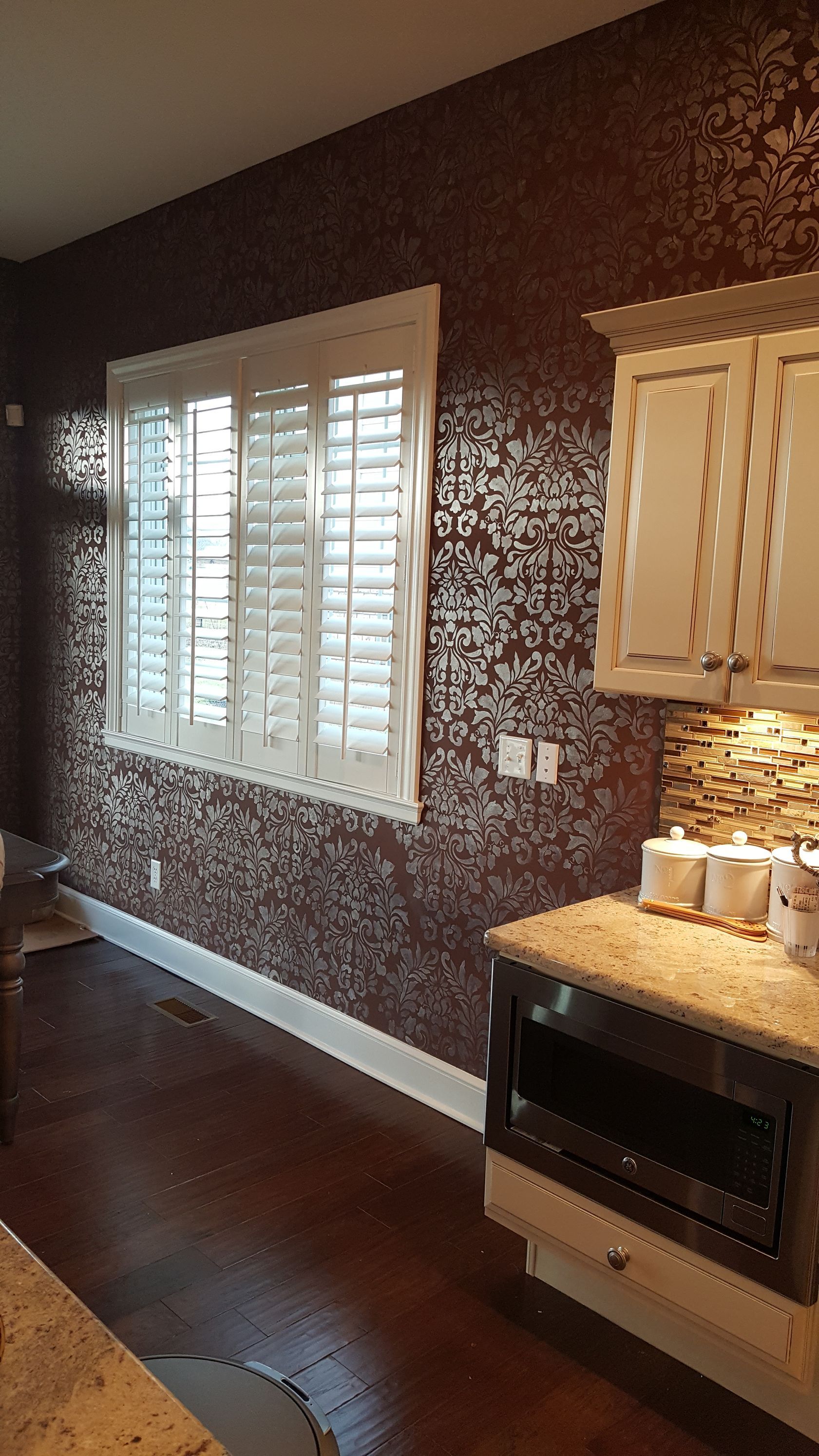 A kitchen with a window and shutters on the wall.