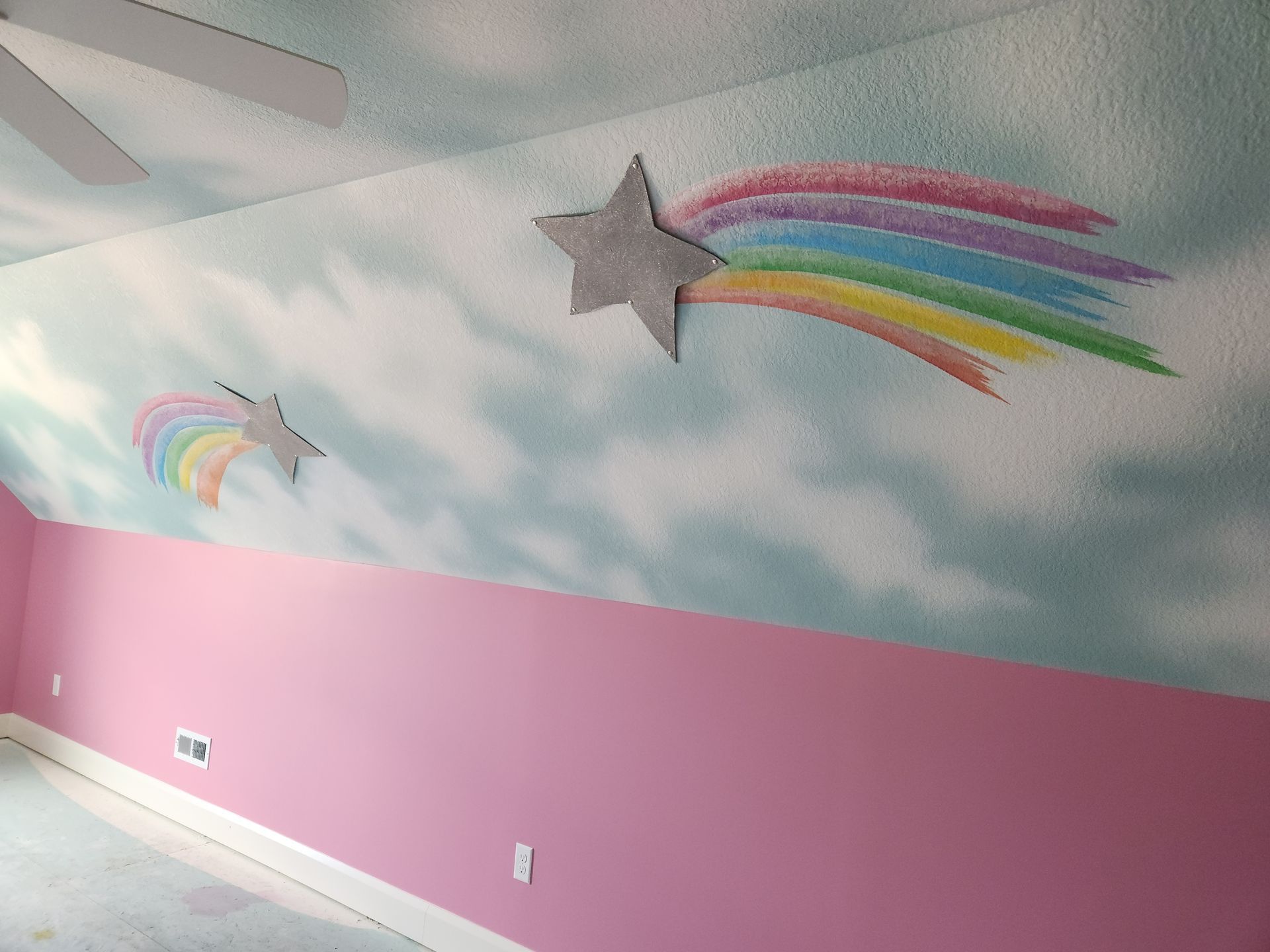 A ceiling with a rainbow and stars painted on it. artist kids room