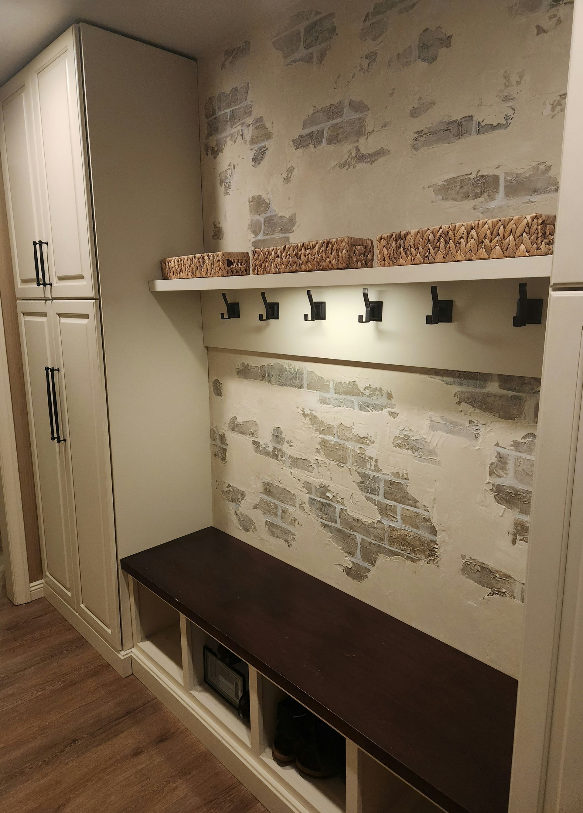 A hallway with a bench and a shelf with hooks on the wall.
