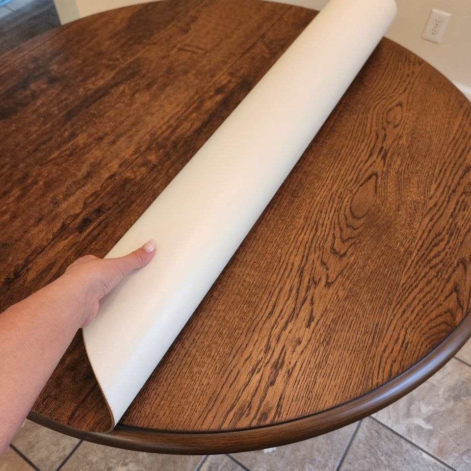 A person is holding a roll of paper on a wooden table