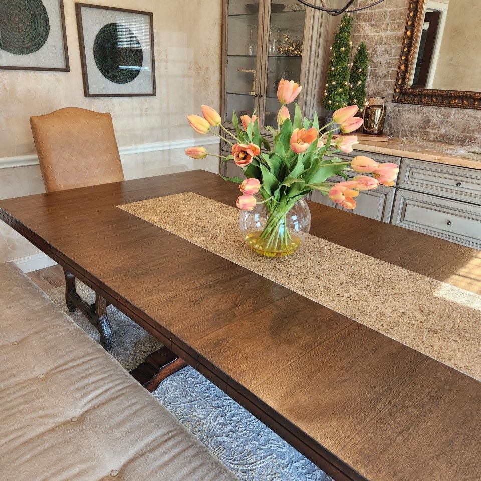 A dining room table with a vase of flowers on it
