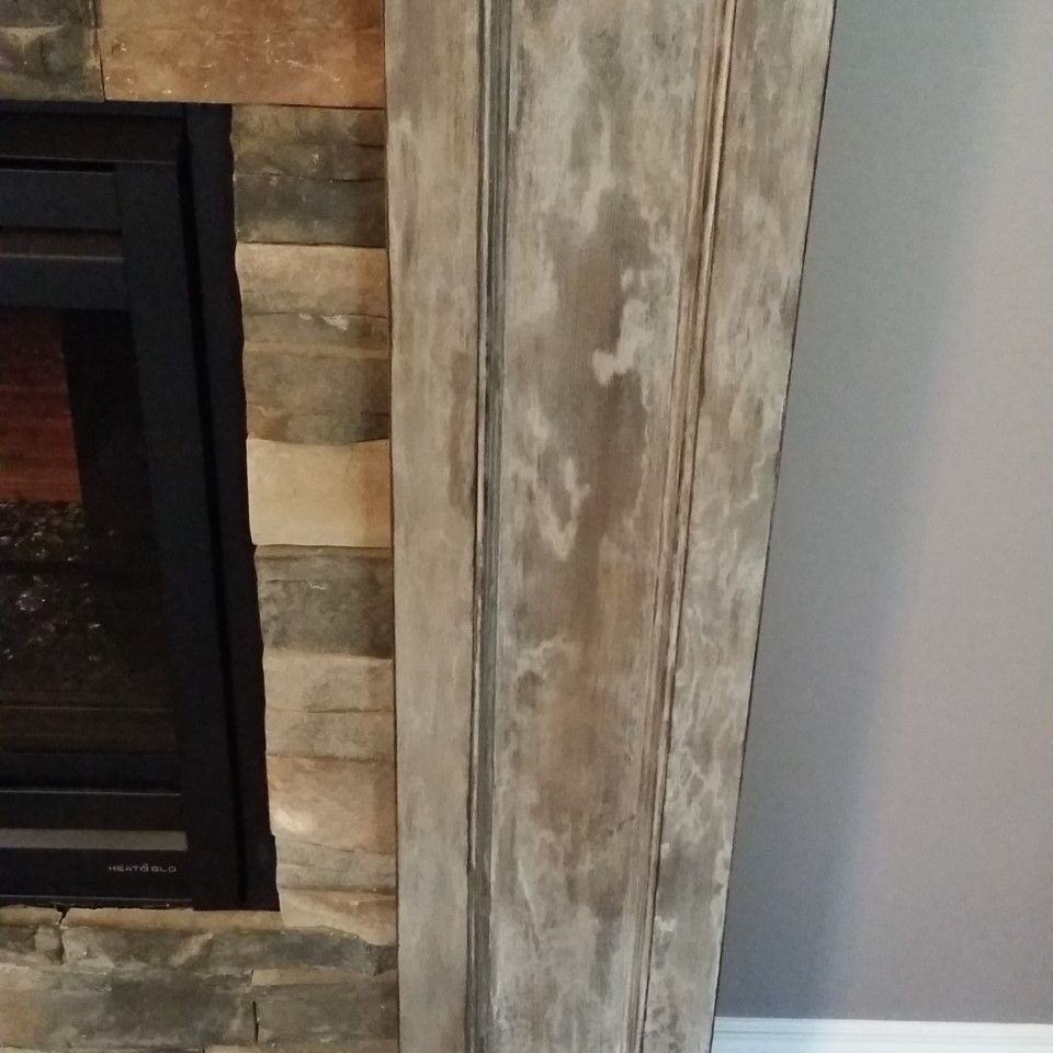 A fireplace with a wooden mantel painted  in front of it