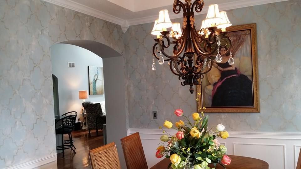 A dining room with a chandelier and a vase of flowers on the table