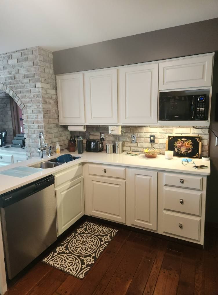 A kitchen with white cabinets , stainless steel appliances , and hardwood floors.