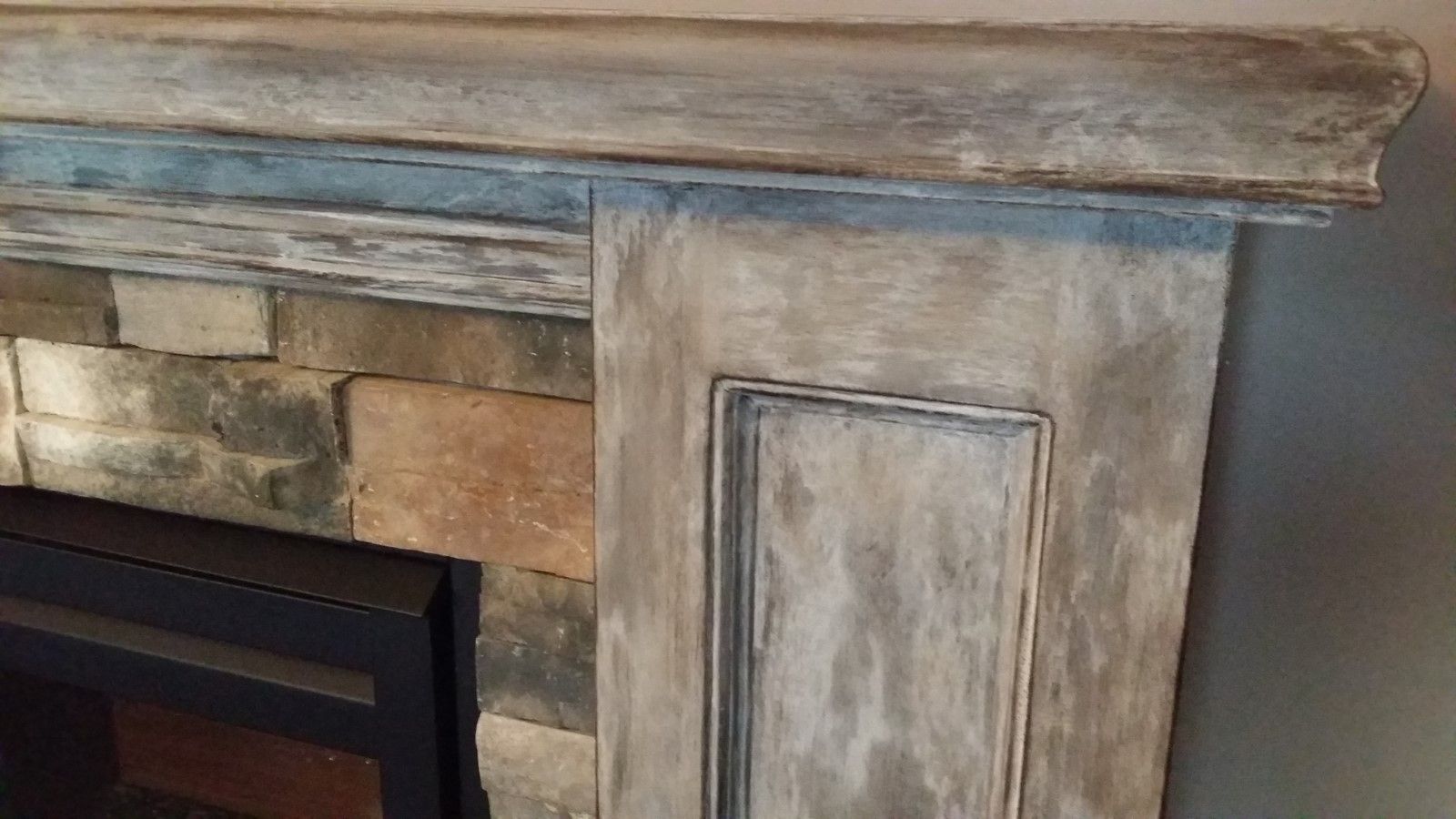 A fireplace with a wooden mantle updated and a brick wall in a living room. 