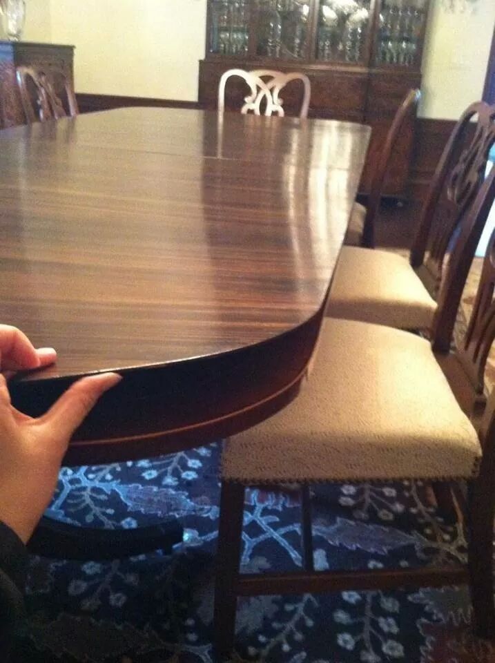 A person is holding a wooden table in a dining room