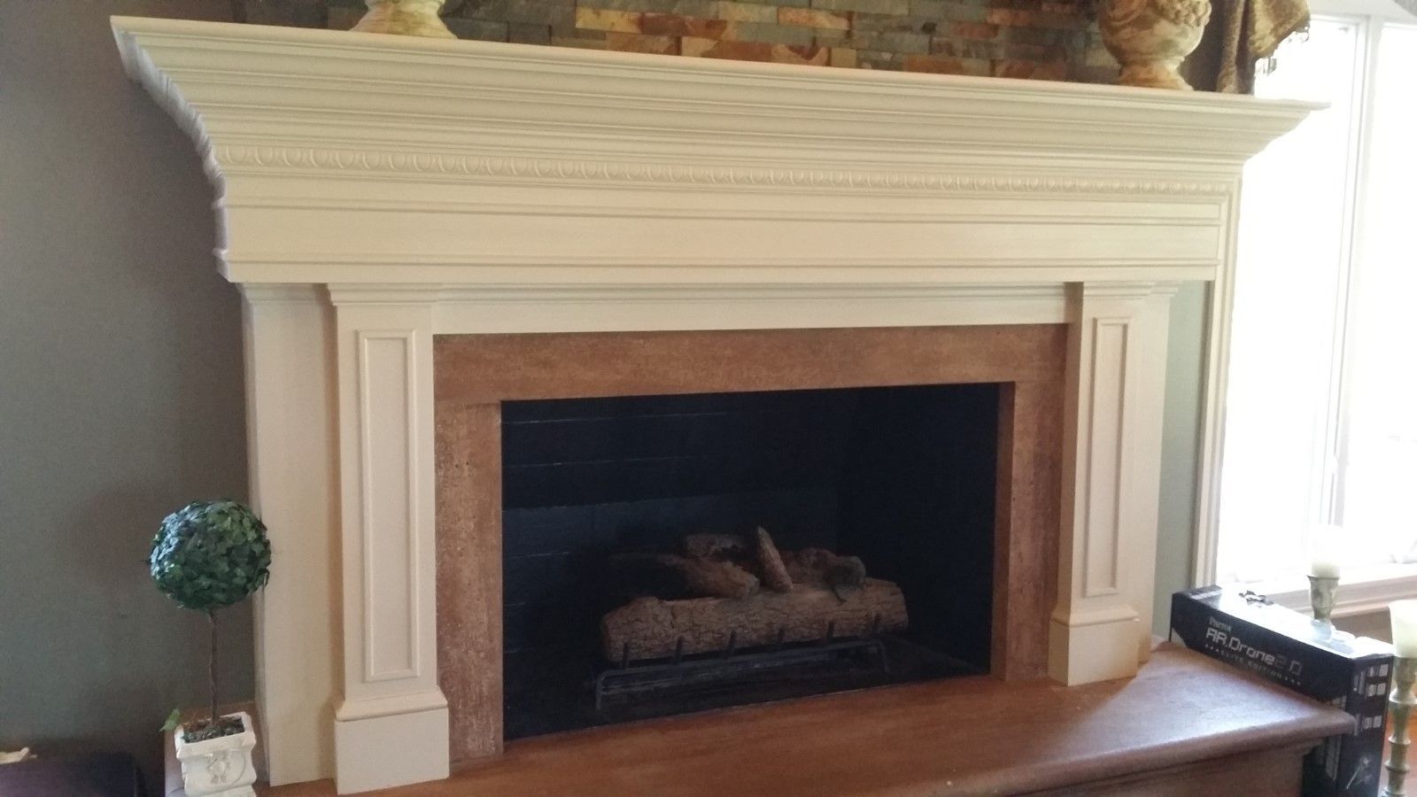 A living room with a fireplace and a mantle painted cream to update.