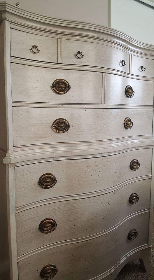 A white dresser with brass handles is sitting in a room.