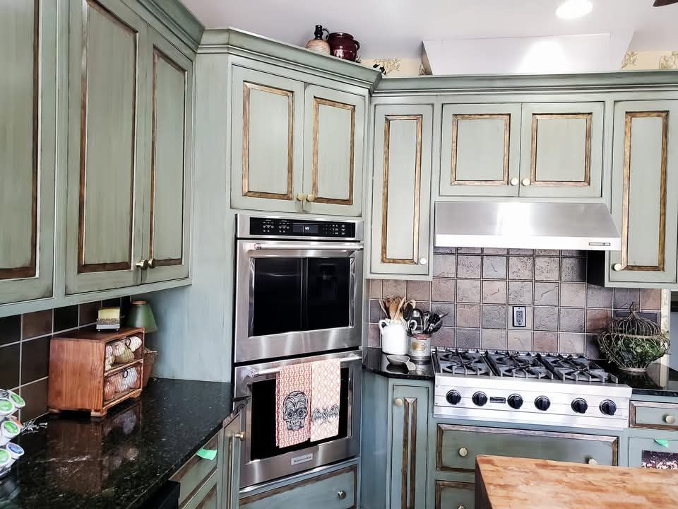 A kitchen with green cabinets and stainless steel appliances update old kitchen cabinets.