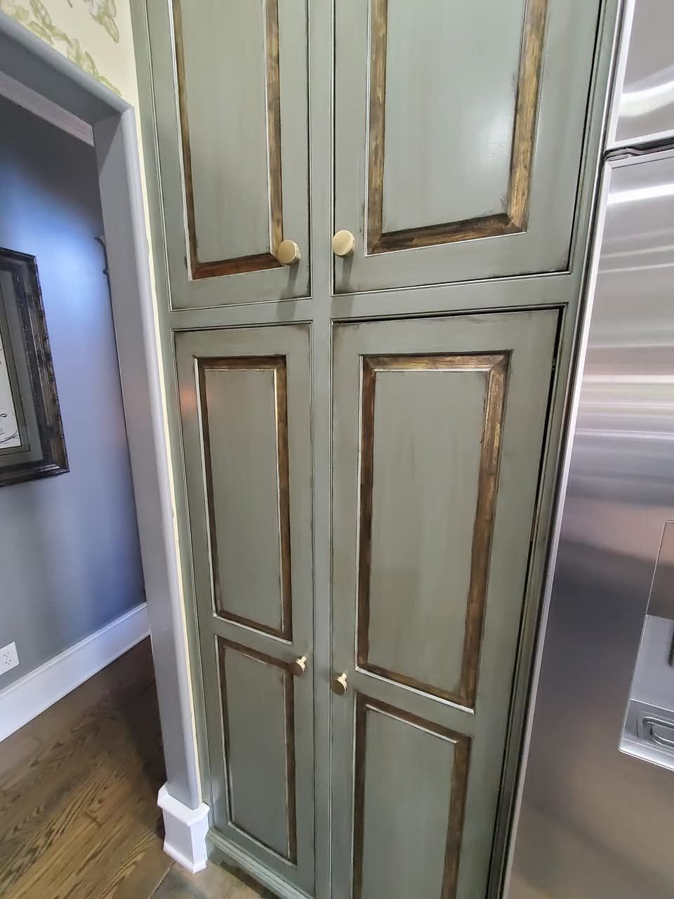 A kitchen with a stainless steel refrigerator and a green cabinet.