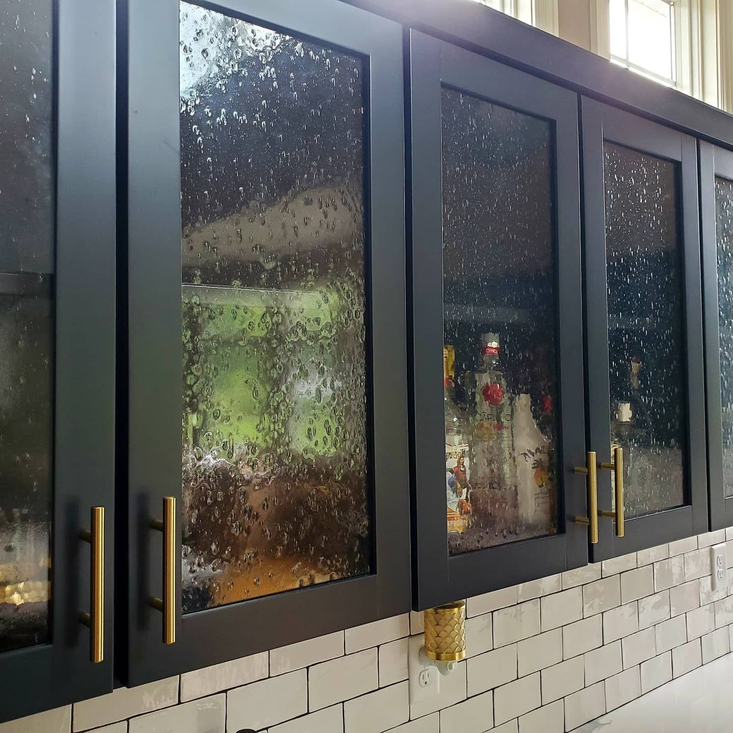 A kitchen with black cabinets and glass doors