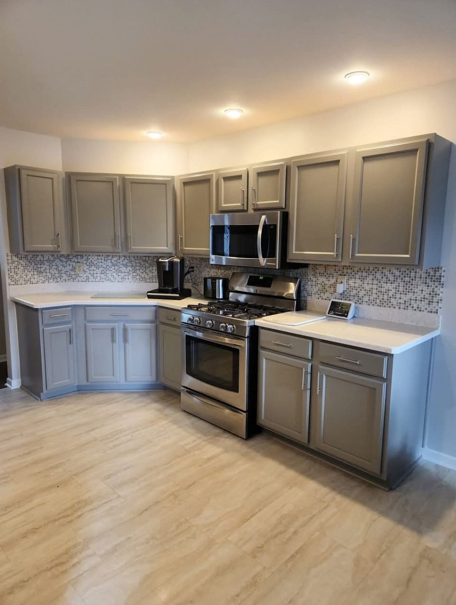 A kitchen with gray cabinets and stainless steel appliances.