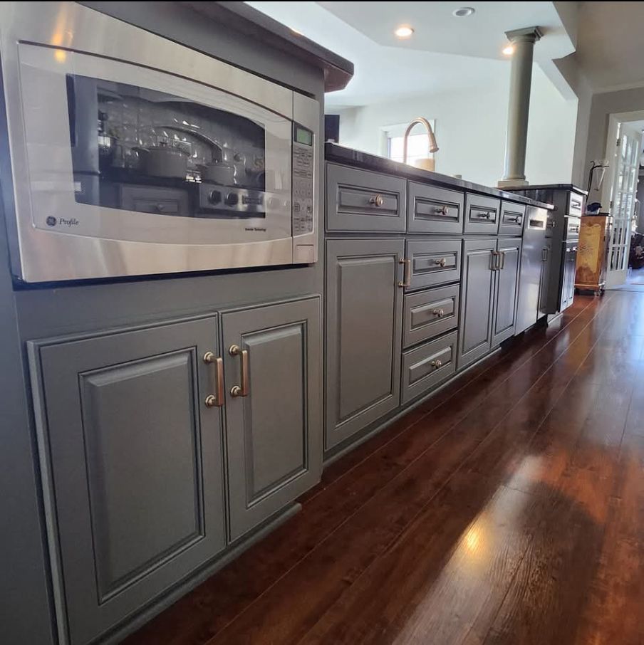A kitchen with gray cabinets and a stainless steel microwave