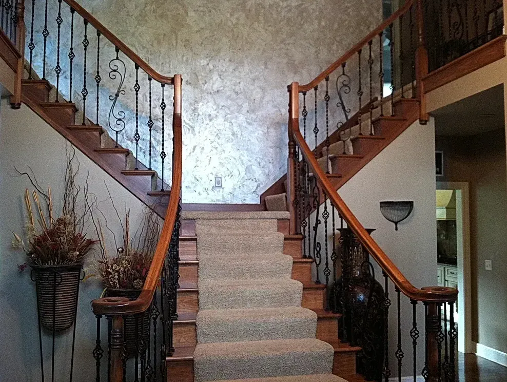A staircase with a carpeted staircase and a wrought iron railing