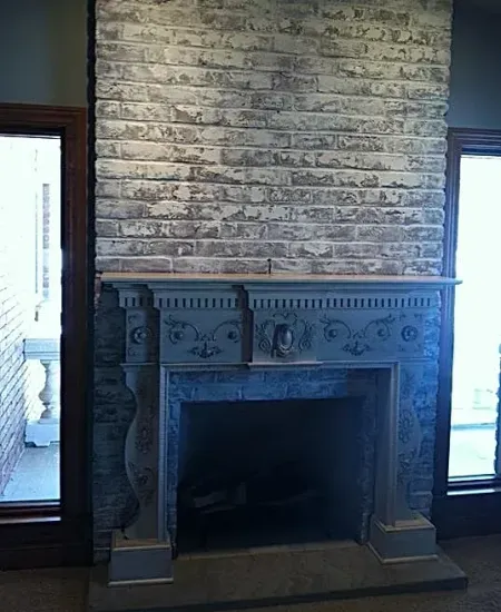 There is a fireplace in the middle of the room with a brick wall behind it.
