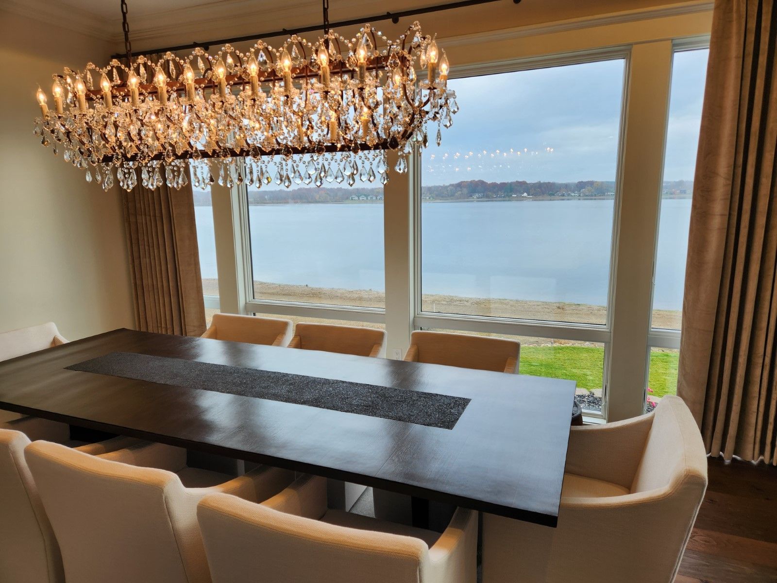 A dining room with a large table and chairs and a view of the ocean.