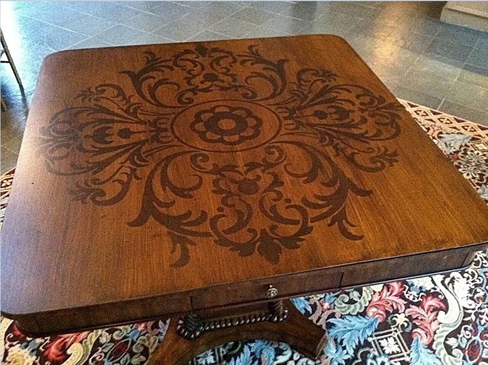 A wooden table with a floral design on it is sitting on a rug.