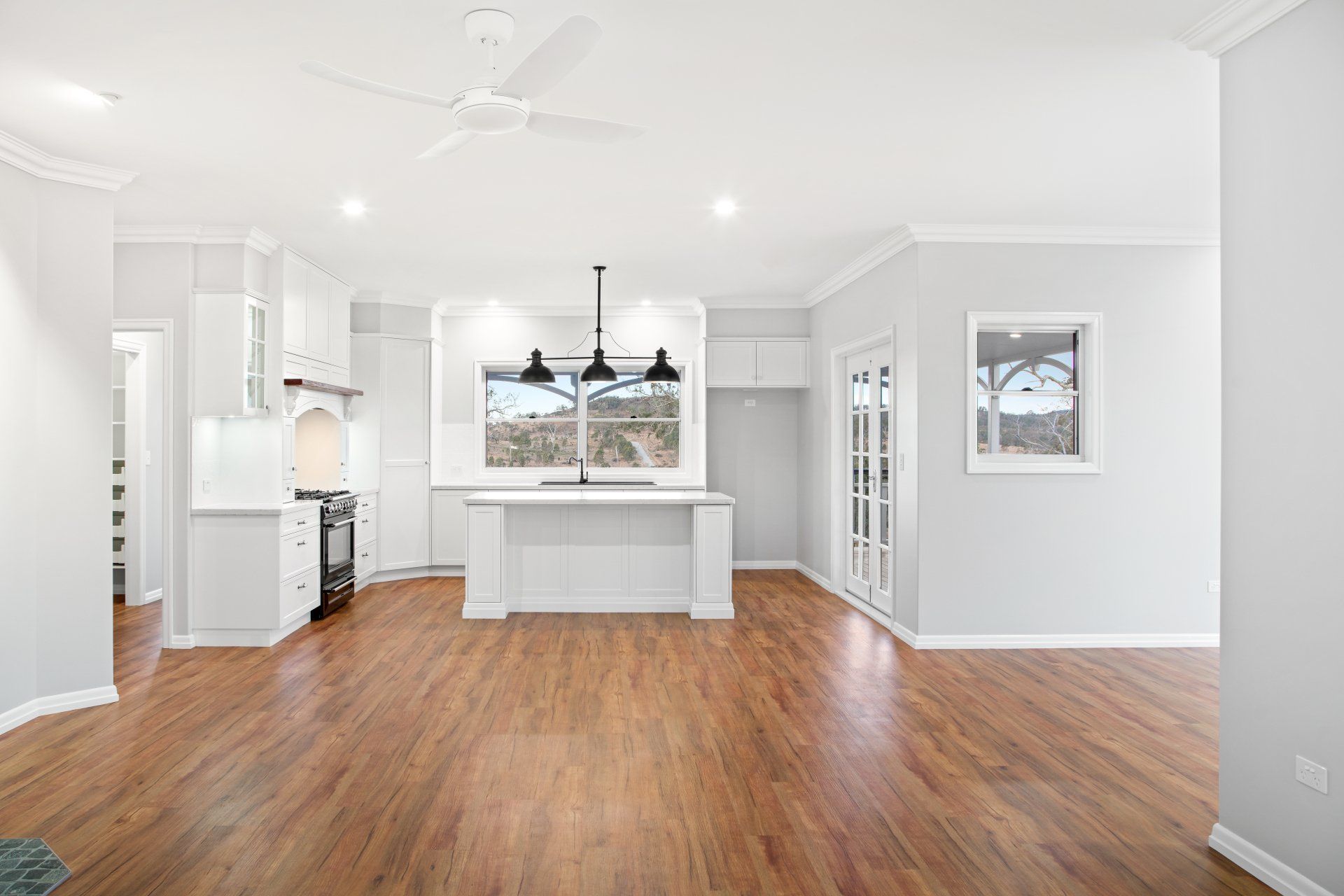 Open-concept kitchen and living area with hardwood floors, white cabinets, and island.