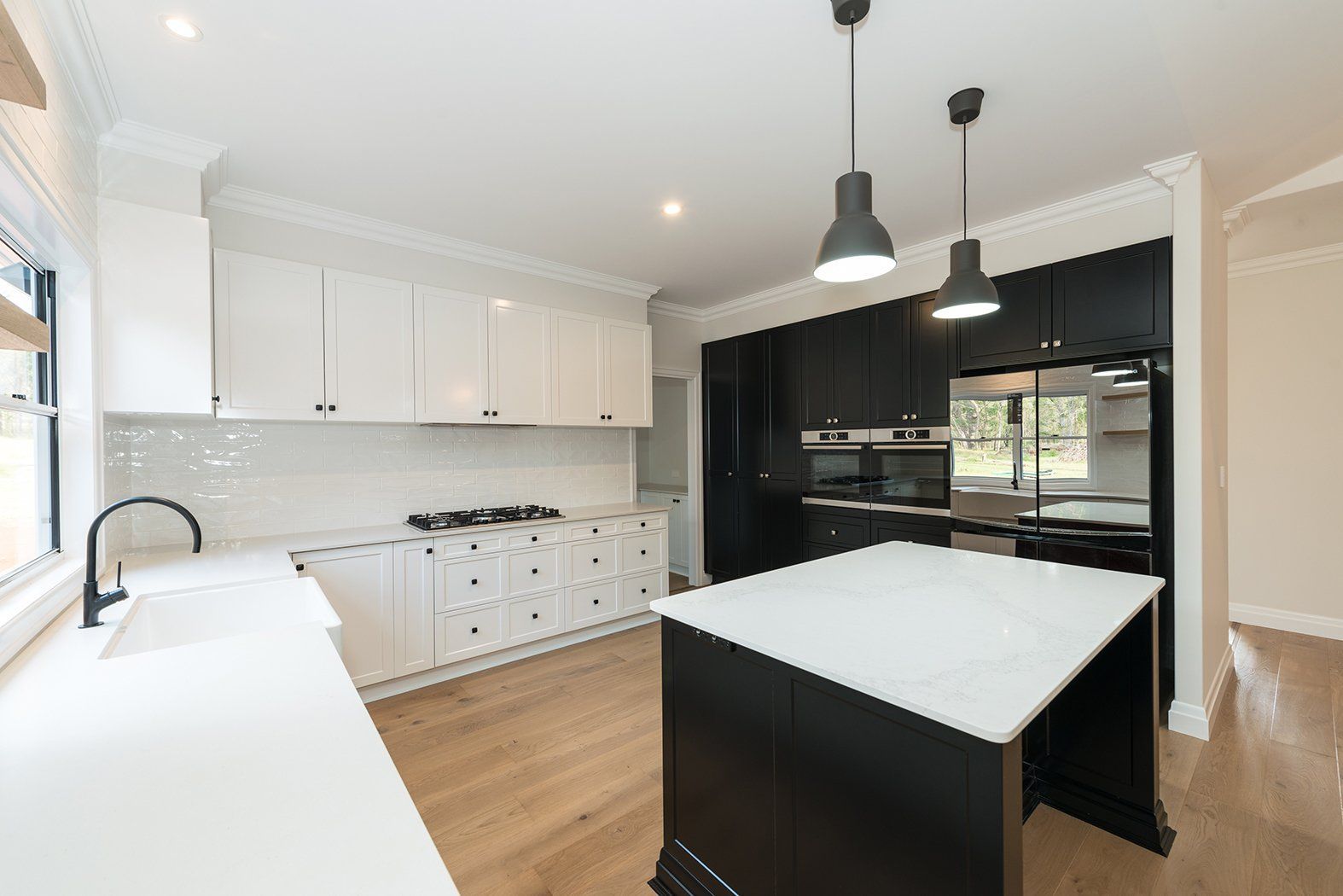 Modern kitchen with white countertops and cabinets, black island, and stainless steel appliances.