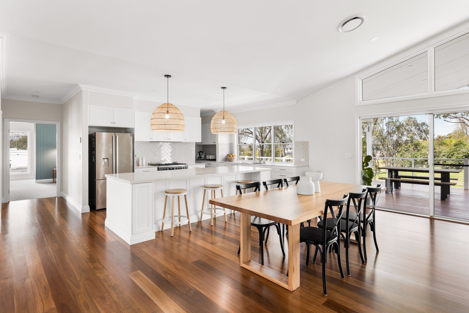 Spacious, bright kitchen and dining room with hardwood floors, a large island, and a table set for a meal.